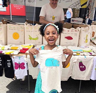 A young girl proudly holds up her Bugged Out t-shirt