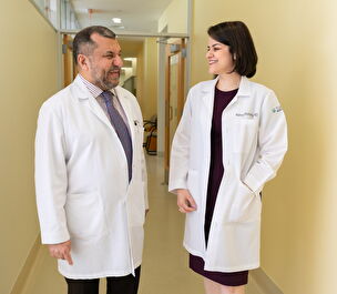 Two scientists standing in a corridor talking and laughing