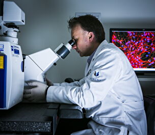 A male scientist looks in a microscope