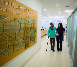 A trial participant walks down a hallway with the assistance of a cane