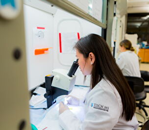 A researcher looks into a microscope